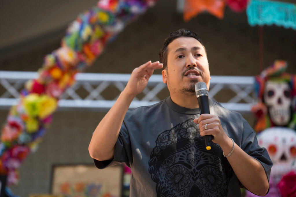 A man speaking outdoors talking into a microphone