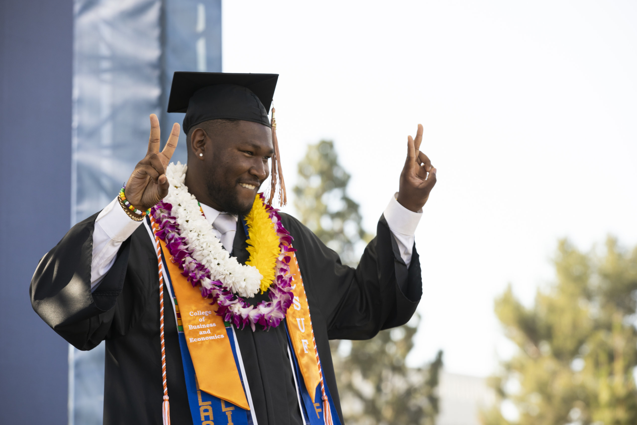 Happy graduate shows peace sign from stage