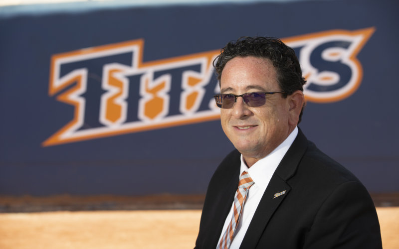 man wearing a dark suit, orange and white tie and sunglasses