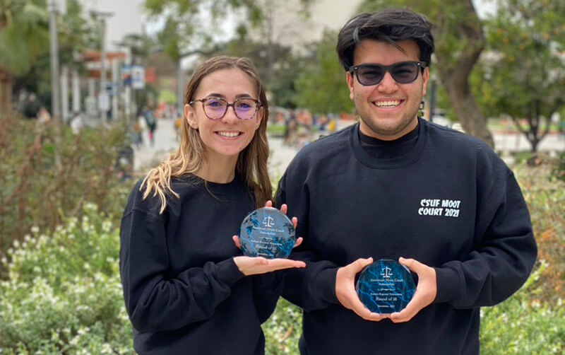 Amaris Aloise and Kayhan Bakian hold awards for their speaking skills in a Supreme Court simulation