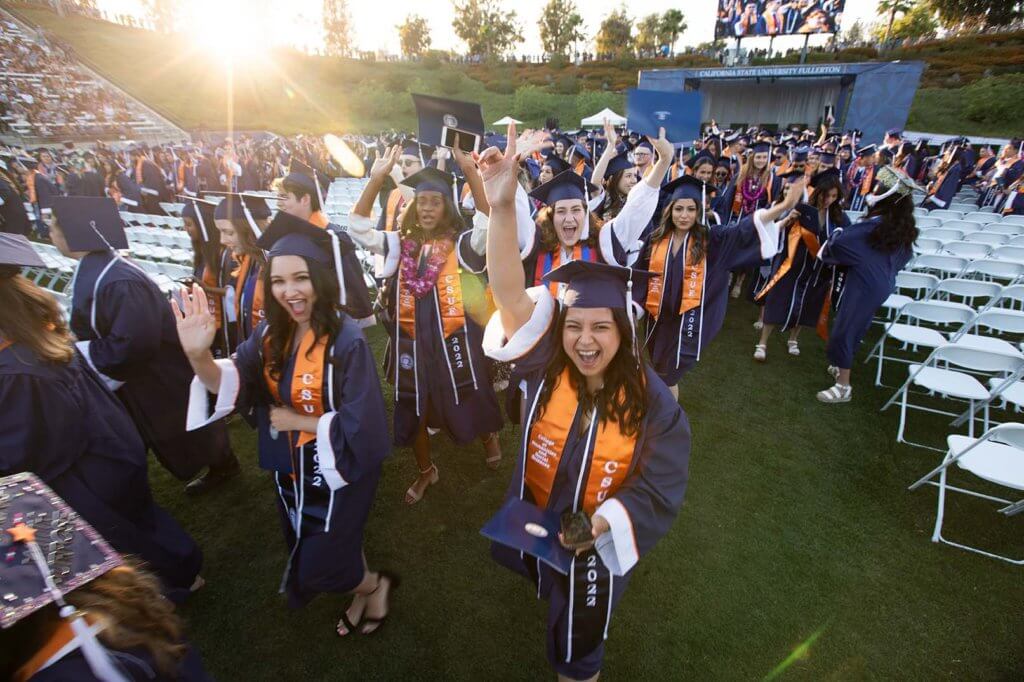 College of Humanities and Social Sciences graduates leave the stadium holding up their diplomas