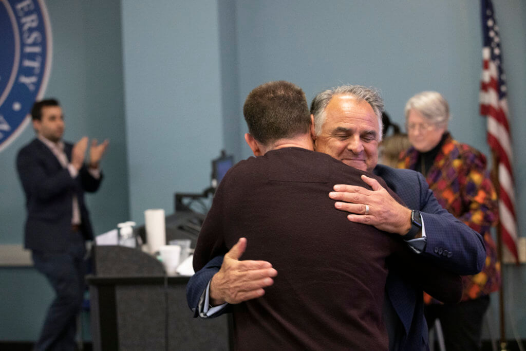 President Virjee hugs Craig Loftin, the 2023 Outsanding Lecturer
