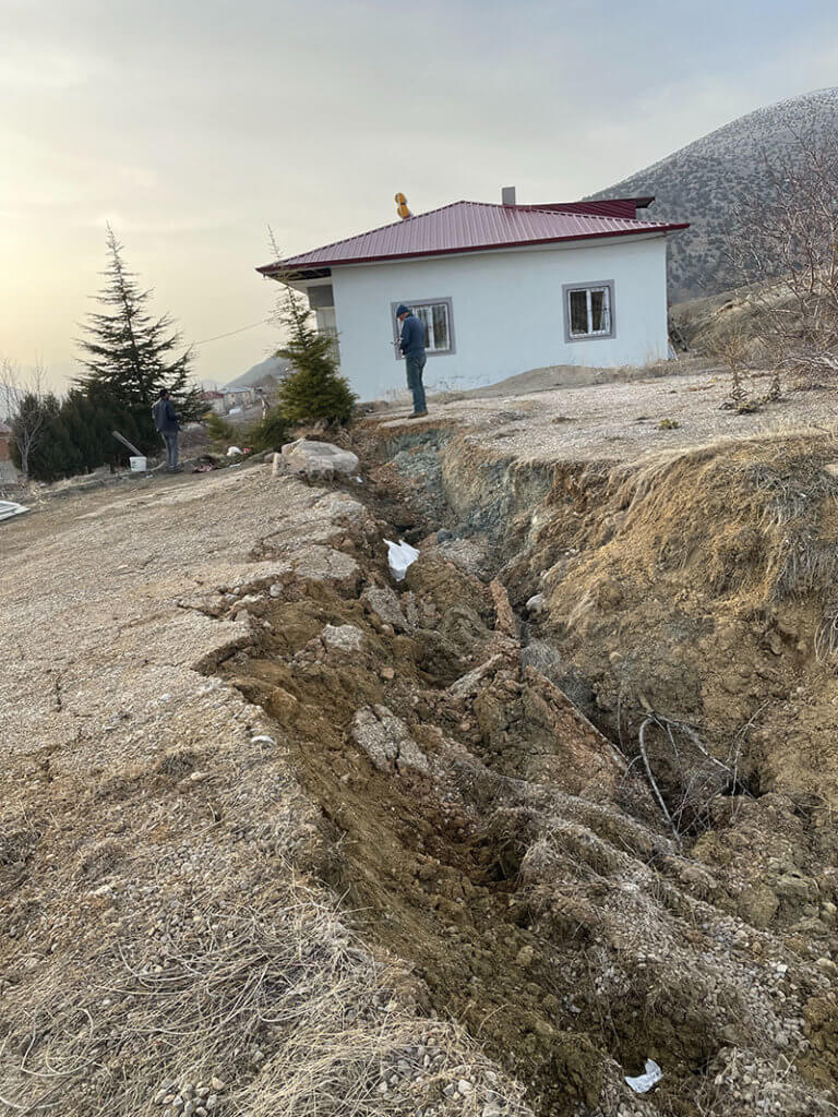 Man stands on the edge of a surface fault rupture