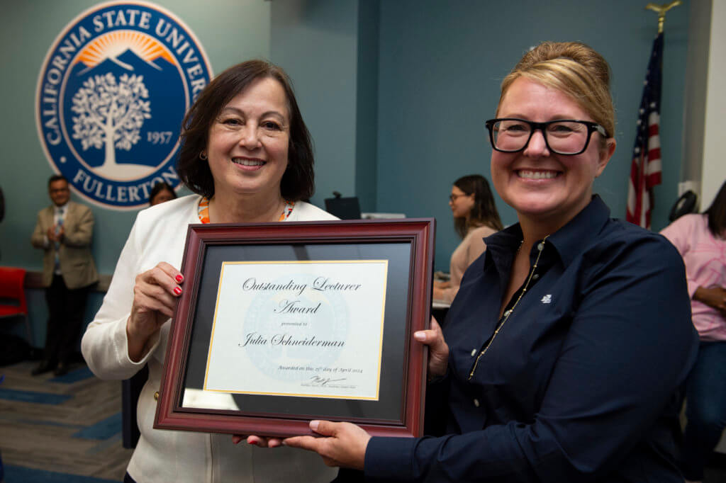 CSUF President Sylvia Alva, left, presents Julia Schneiderman, lecturer in human communication studies, with the 2024 Outstanding Lecturer Award at the April 25 Academic Senate meeting