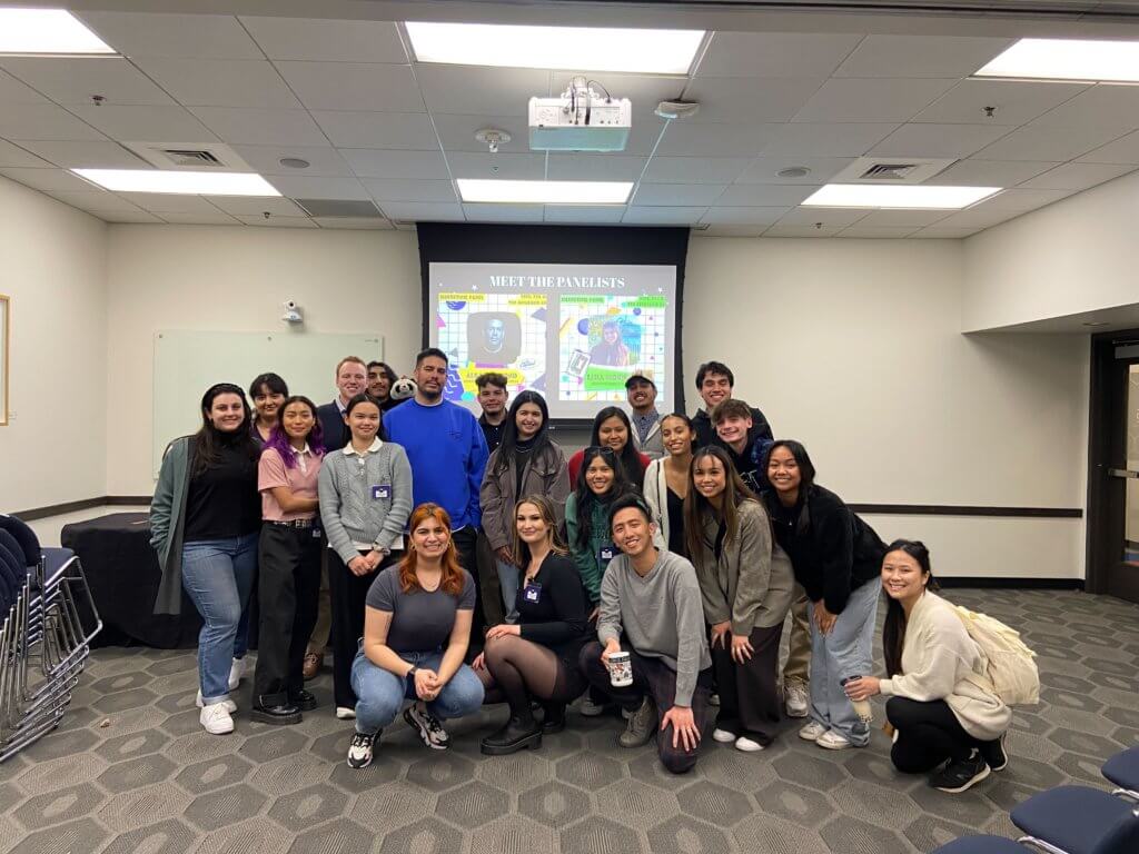Mingyu Wu with a group of students in CSUF's Music Industry Club, standing in a a room in front of a projector screen that shows pictures of the event's panelists. 