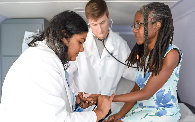 Two Ross University students check on a patient