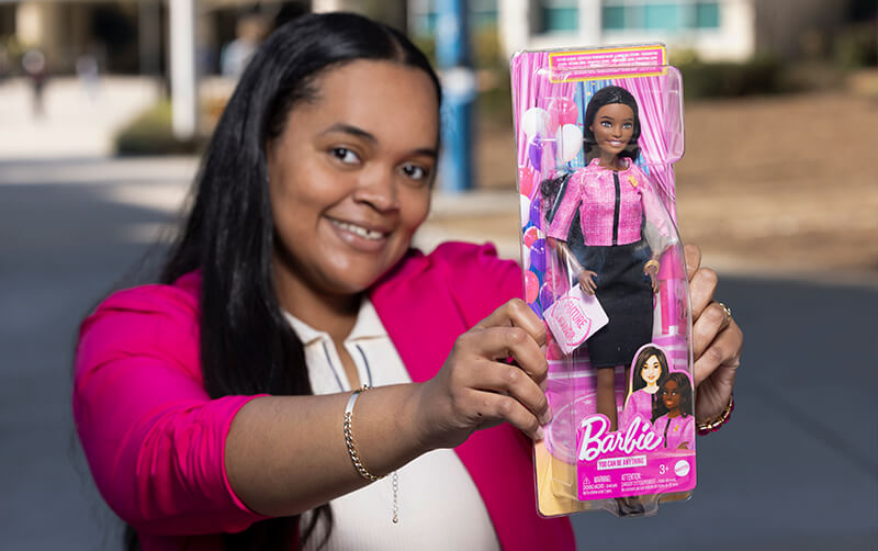 CSUF student Amirah Kambe holding a Black Barbie doll