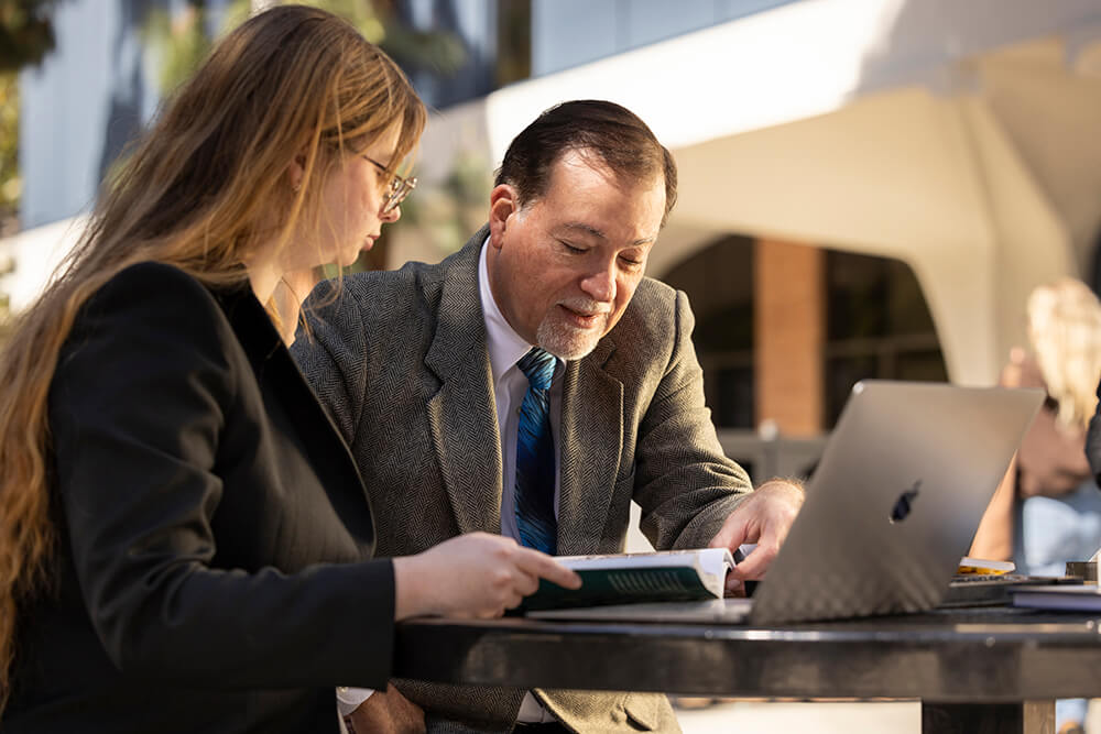 Natalya Rowe and Paul Simoes look at history books outside of the College of Humanities and Social Sciences.