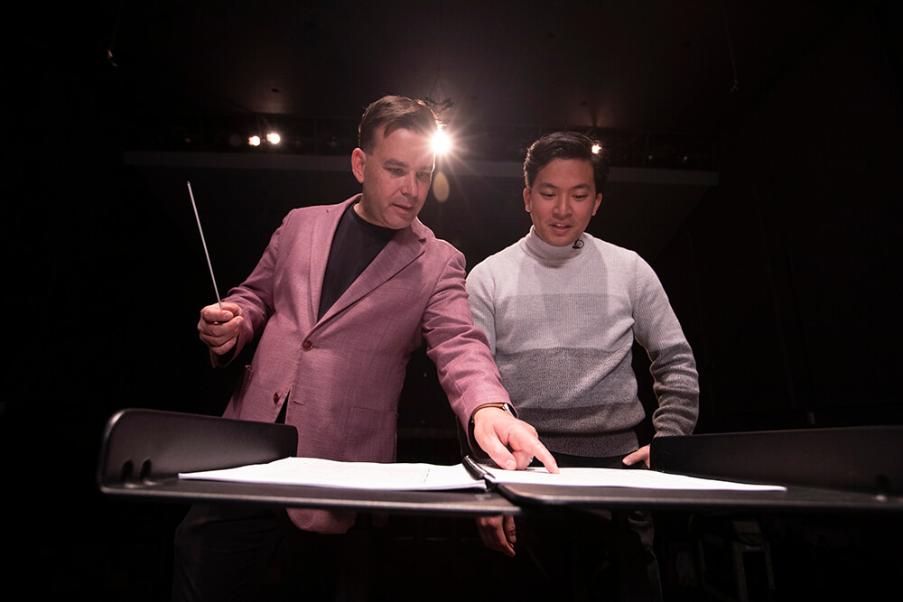 O maestro musical Johnston Nguyen, estudando o vento instrumental condutor, e o professor Dustin Barr