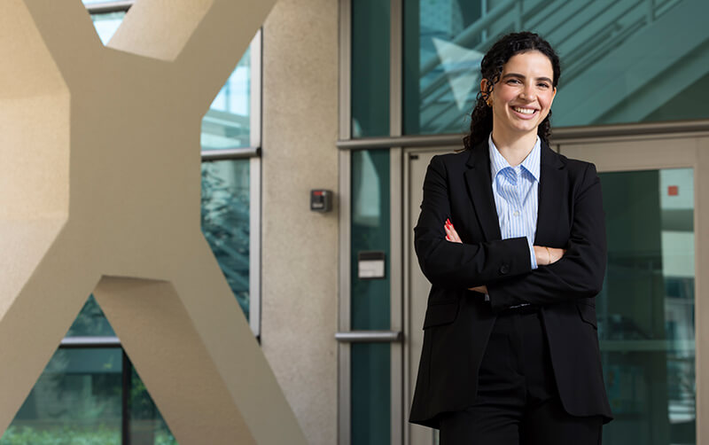 Doctoral nursing student Fajer Al Najjar standing with arms crossed.