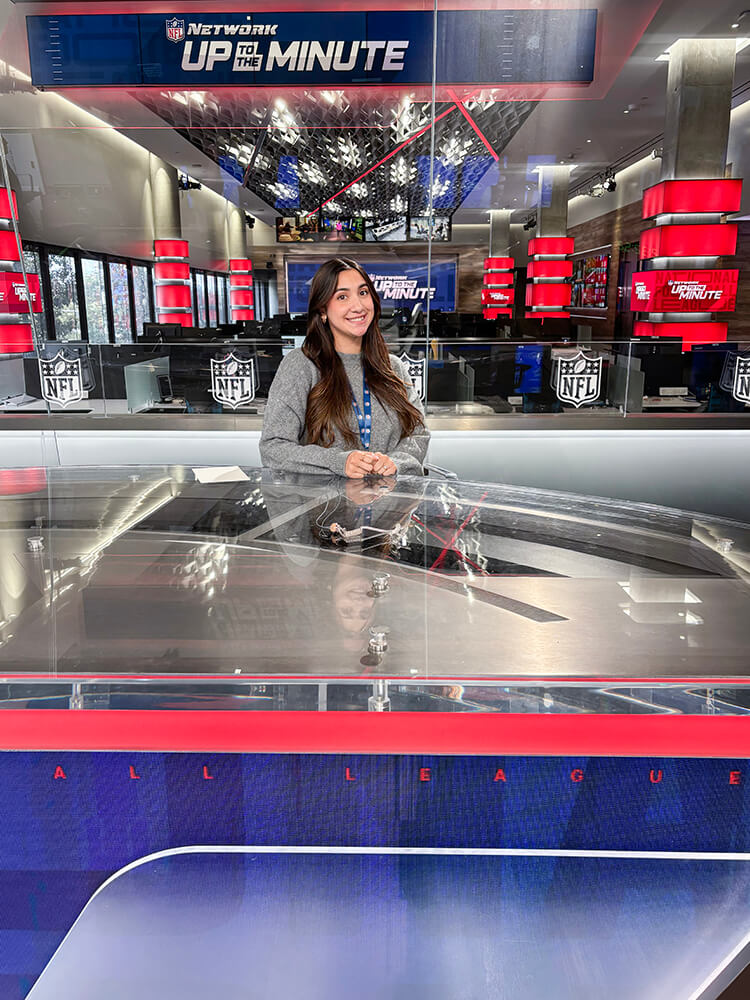 Isabella Kechezian se sienta detrás del mostrador de noticias en la red de la NFL.