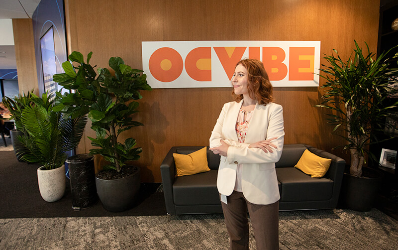 Cal State Fullerton alum Emily Sharp poses in business attire in an office of the OCVIBE development.
