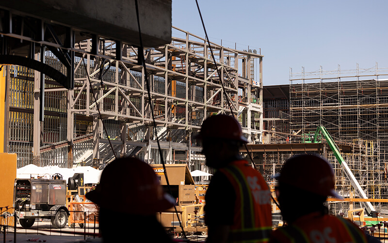 Three people in hard hats tour construction at the OCVIBE development in Anaheim.