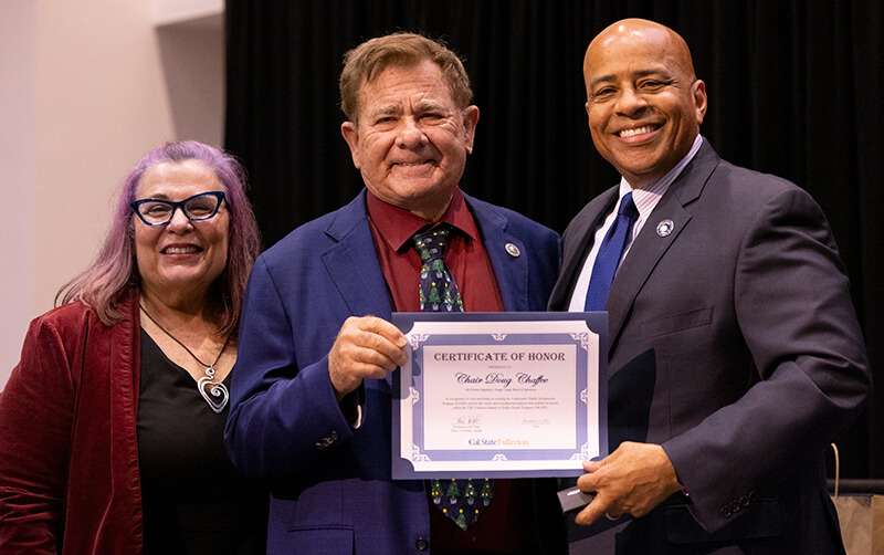 Michele Wood, Doug Chaffee and Ronald Rochon hold a certificate and pose for a photo in the Titan Student Union Portola Pavilion.