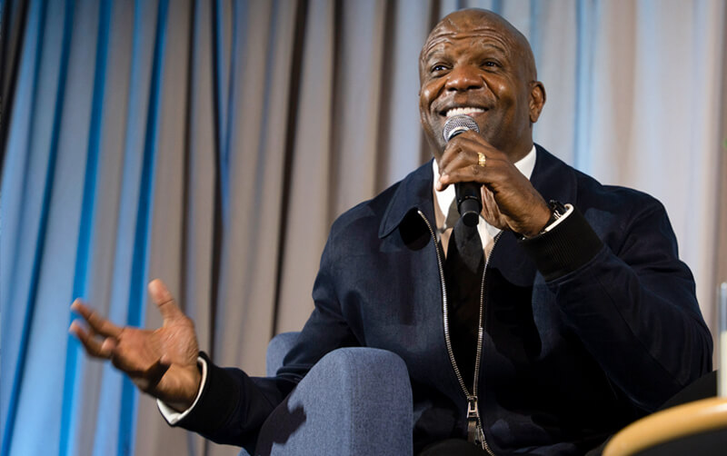 Terry Crews talks into a microphone on stage in the Titan Student Union.