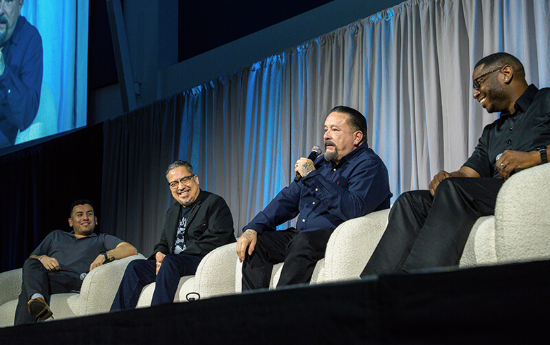 Ricardo Pitones, assistant director of the Latinx Community Resource Center and HSI student initiatives; Alexandro Gradilla, associate professor of Chicana and Chicano studies; Mister Cartoon; and JC Cavitt, executive director of Project Rebound participate in a panel discussion on stage in the Titan Student Union Portola Pavilion