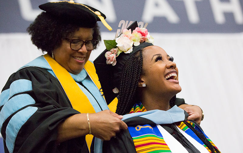 Graduate being presented with master's sash.