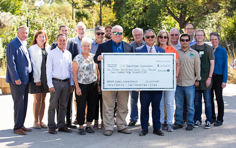 Campus Community Memebers gather around giant check.