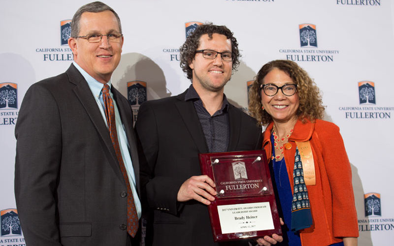 Three adults — Brady Heiner, Mildred Garcia and John Biesner — stand together at awards ceremony.