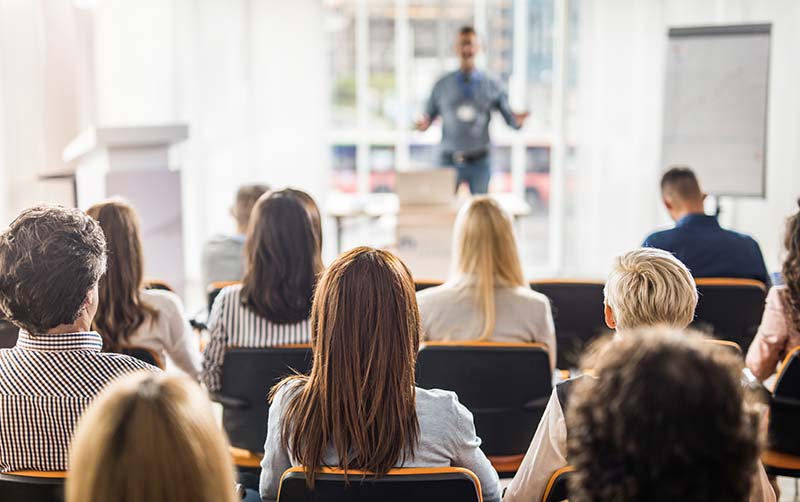 Back view of large group of people having a training class in a board room