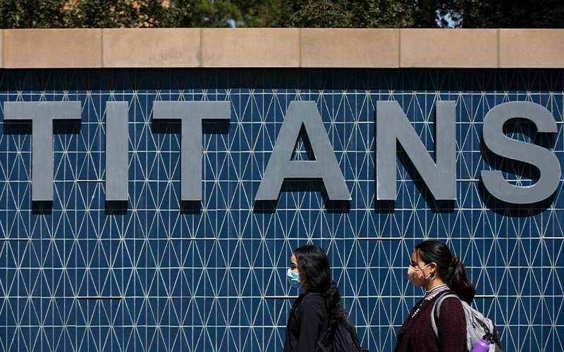 Masked students in front of Titans sign.