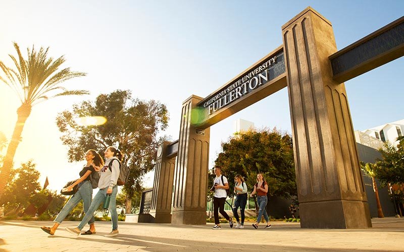 Sunset on the campus gateways with students walking underneath.