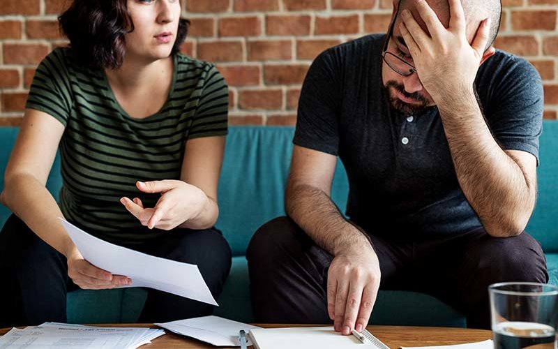 Stressed couple arguing over bills.