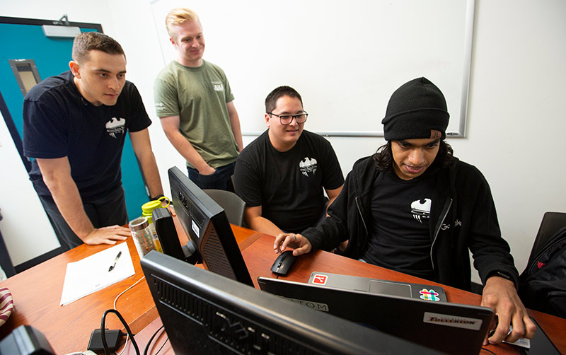 Student Shripal Rawal, right, and other cybersecurity students work on computer.