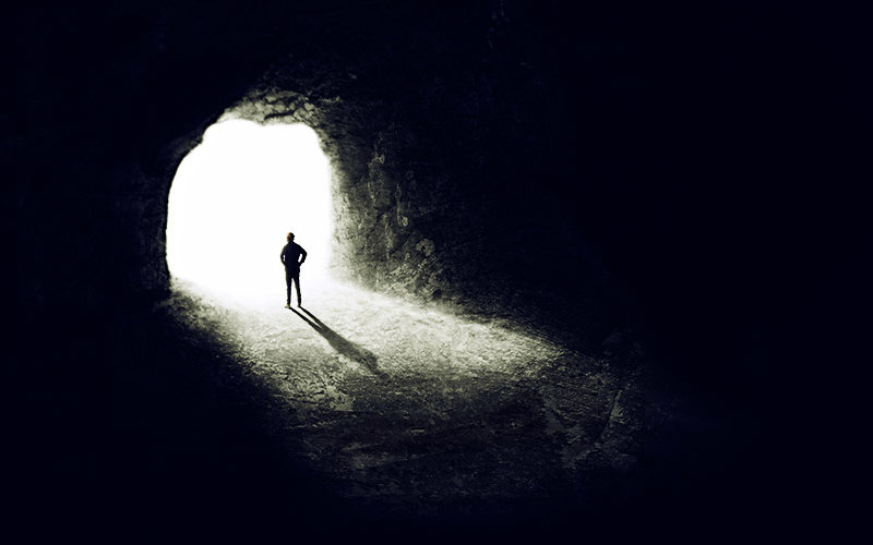 person standing in tunnel with light