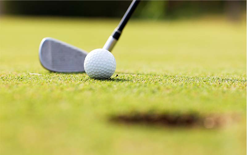 Golf game with focused ball on the golf course.