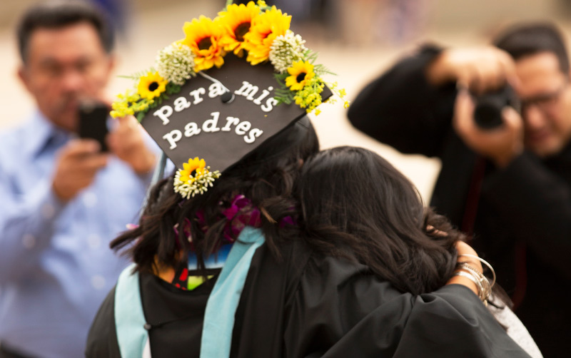 Latina Graduate hugging family memeber.