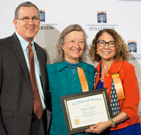 CSUF President Mildred Garcia, woman, and CSUF's John Bisener, man, congratulating biochemist Maria Linder, woman, all smiling