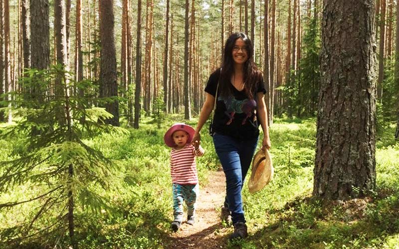 Nga Nguyen walking through forest with child.