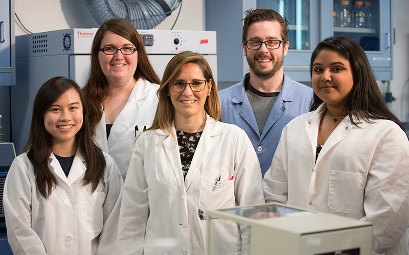 Professor and four of her students posing insider her parasite research lab