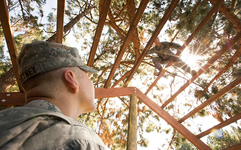 Cadet Andrew McCartney, left, watches Captain Russell Moore as he transverses the Weaver portion of the new obstacle course.