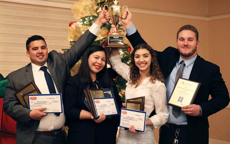 Two men and two women holding trophy.
