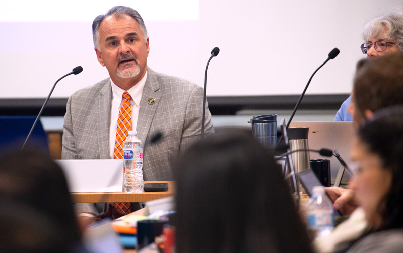 Gray-haired man with goatee speaks on the fiscal state of the University.