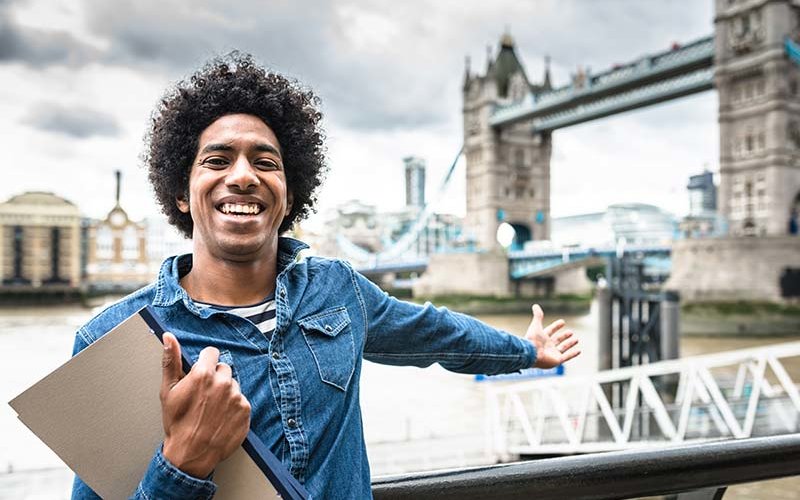 African American student poses in front of the Tower Bridge in London