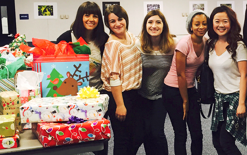 smiling women in a classroom with holiday wrapped gifts