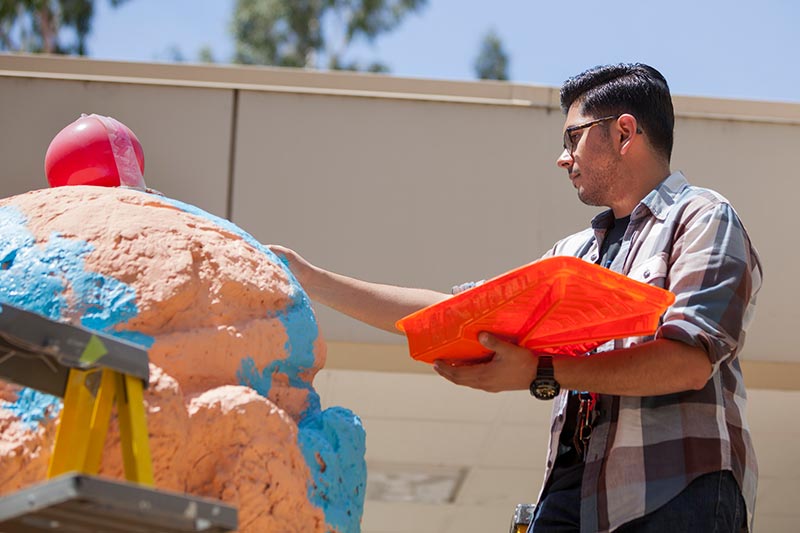 Animation student Omar Gomez paints the ice cream sculpture.