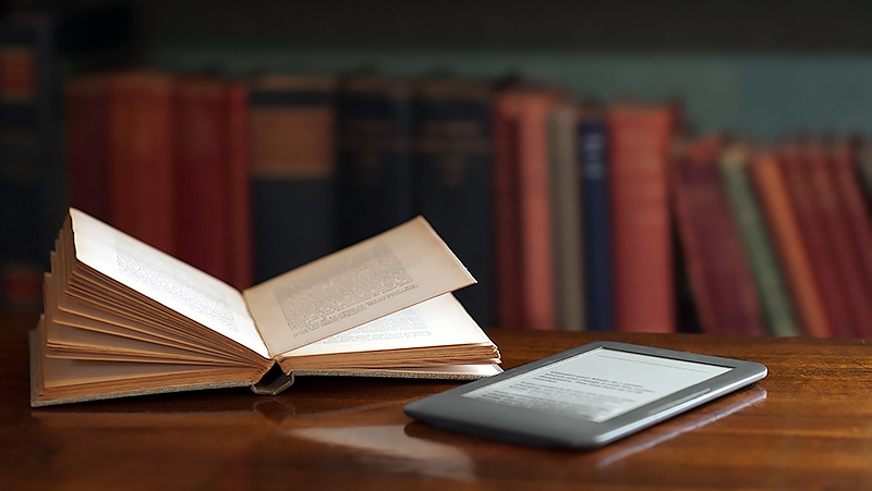 Book and e-reader on table.