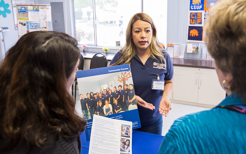 A CSUF health advocate speaks with community members.