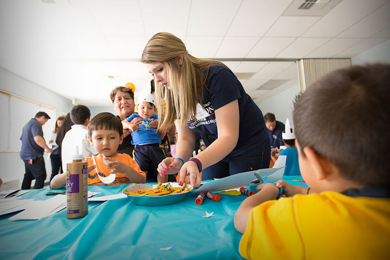 Center of Healthy Neighborhood staff member assisting a boy.