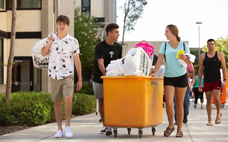Student Ashley Oliva, right, gets help from her brother and boyfriend as she readies to make Cal State Fullerton her new home on Move-In Day.
