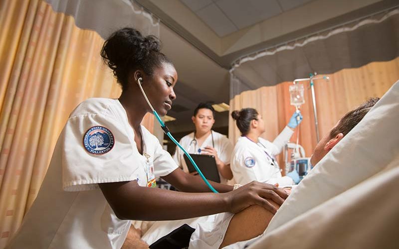 Three CSUF nursing students attending to volunteer patient