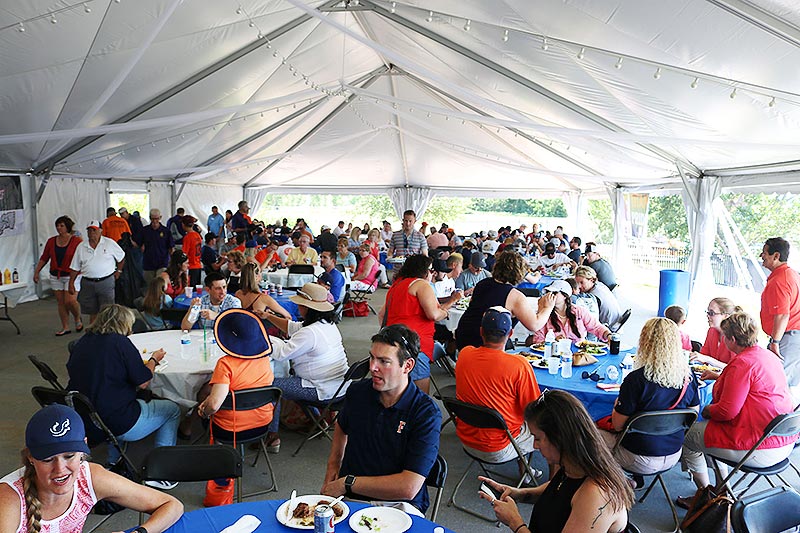 Titans team members and fans gather under tents enjoying barbecue.
