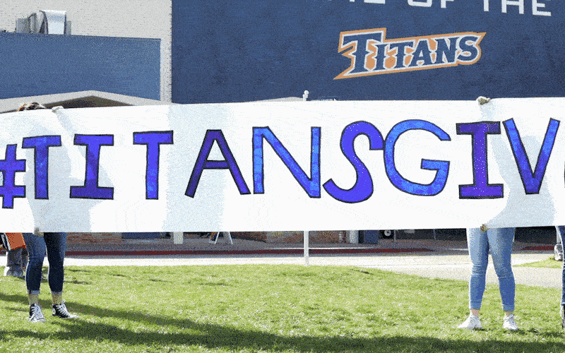 Tuffy running though "#TitansGive" banner
