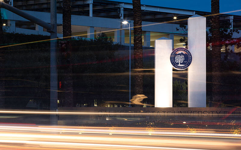 CSUF monument at night with traffic streaming below.