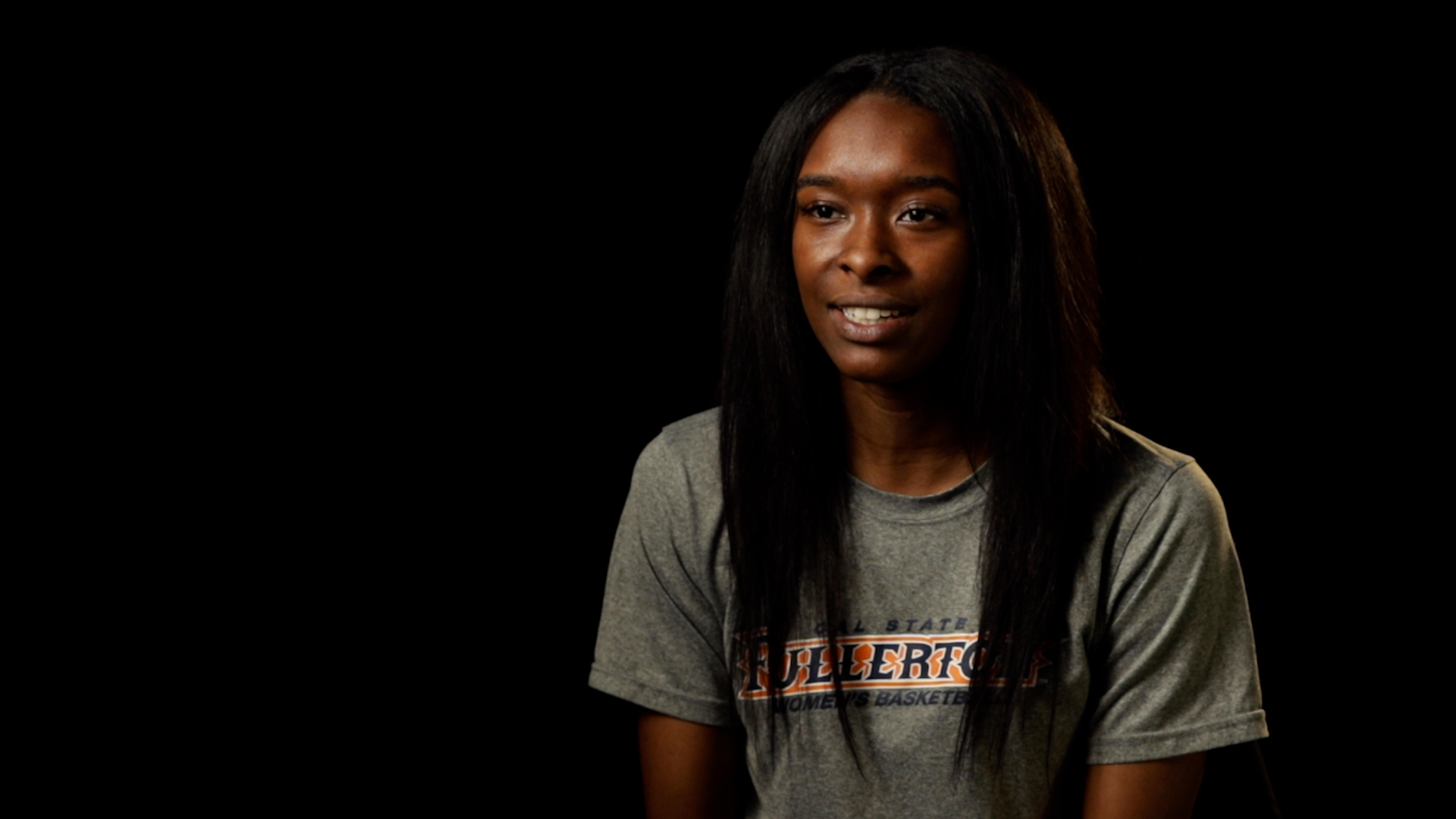 a Black woman smiling in a studio with a black background