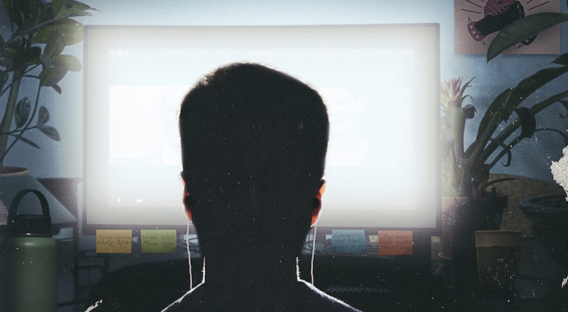 a man staring a glowing computer screen